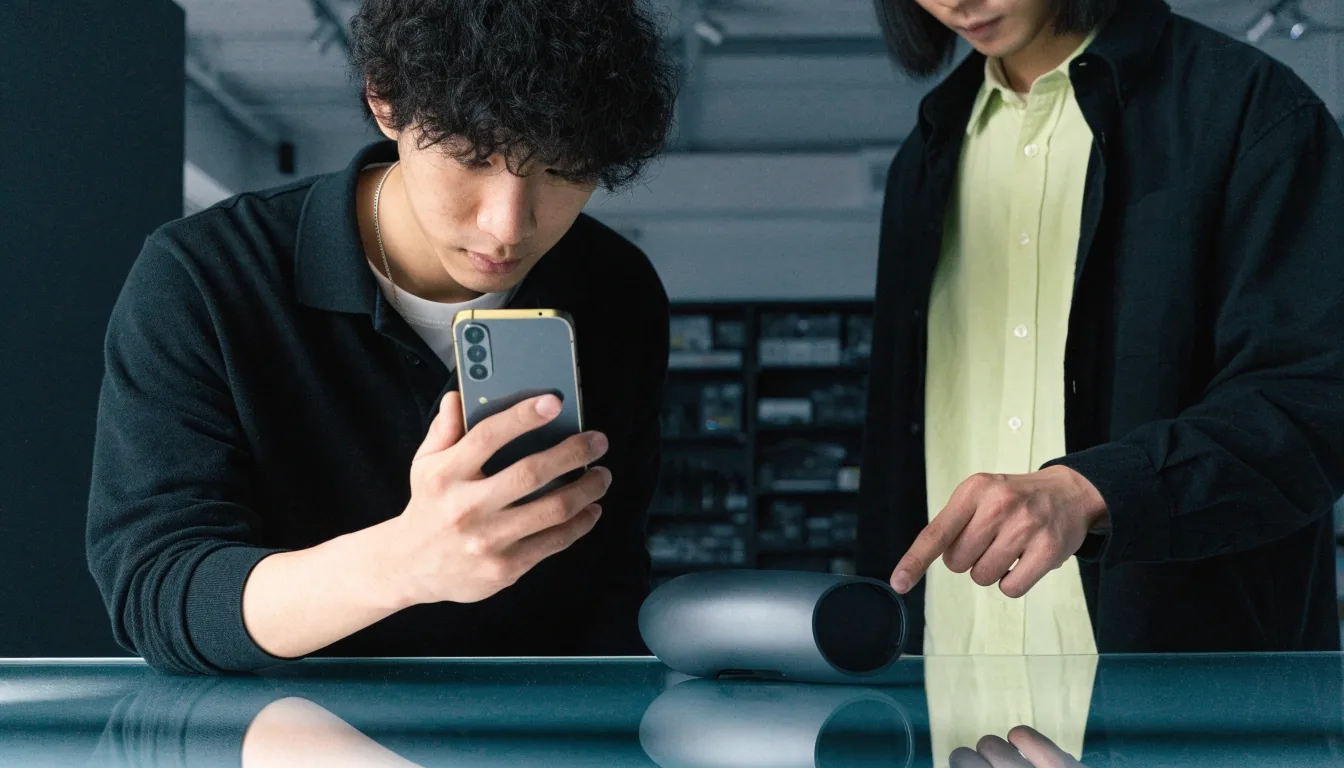 서울 스튜디오 벤치에서 모바일 빌드를 함께 검토하는 두 엔지니어